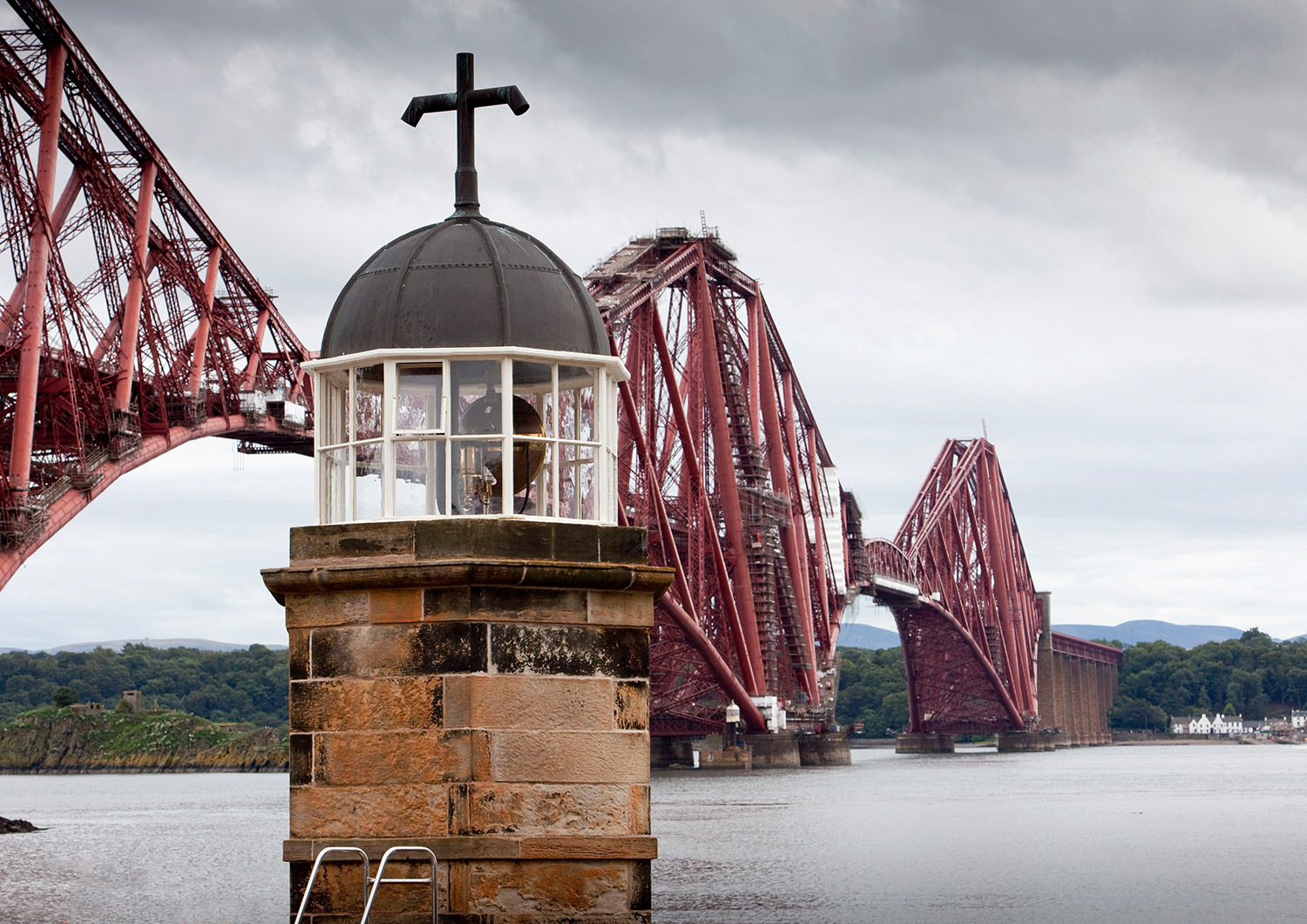 The top of a small light tower, with the Forth Bridge beyond.